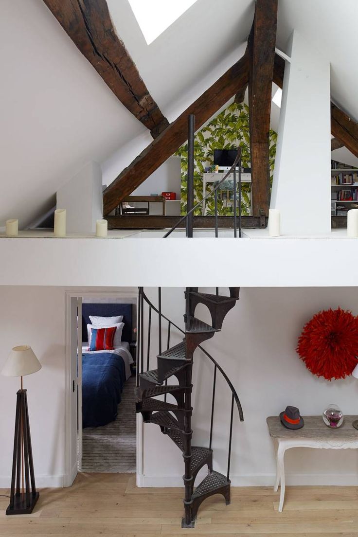 a spiral staircase in the middle of a living room with white walls and wood floors