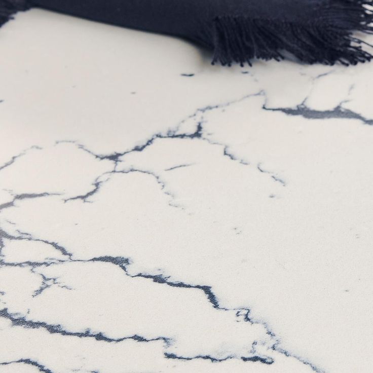 a black scarf laying on top of a white floor covered in snow and ice flakes