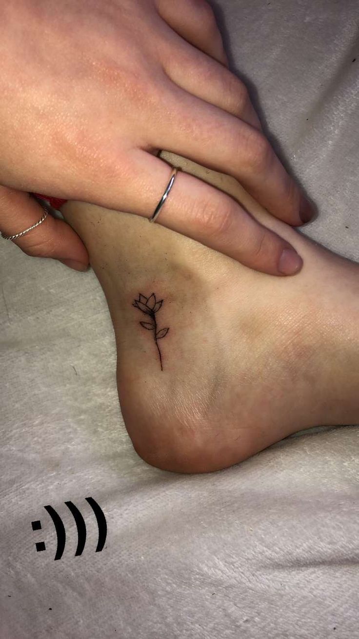 two people with matching tattoos on their feet holding each other's hand and touching the ground