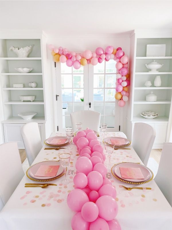 a long table with pink and gold balloons on it is set for a birthday party