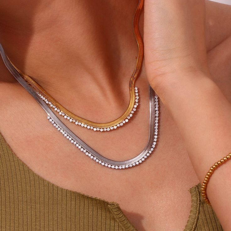 Elevate your look with the Gleaming Edge Herringbone Necklace. Available in both 18-karat yellow gold and 18-karat white gold finishes, this stunning piece is crafted from durable titanium steel. The herringbone chain, adorned with a dazzling array of clear zircons, shimmers beautifully in any light. Perfect for layering or wearing solo, this necklace adds a touch of elegance and sparkle to your ensemble. Whether you choose gold or silver, the Gleaming Edge Herringbone Necklace is your new go-to for a chic and radiant style. Modern Metal Jewelry With Snake Shape, Modern Metal Jewelry In Snake Shape, Stainless Steel Snake Chain Jewelry, Tarnish Resistant Stainless Steel Snake Chain Jewelry, Elegant Herringbone Clavicle Necklace, Elegant Metal Herringbone Clavicle Necklace, Yellow Gold Stainless Steel Snake Chain Jewelry, Elegant Stainless Steel Snake Chain Necklaces, Elegant Stainless Steel Snake Chain Necklace