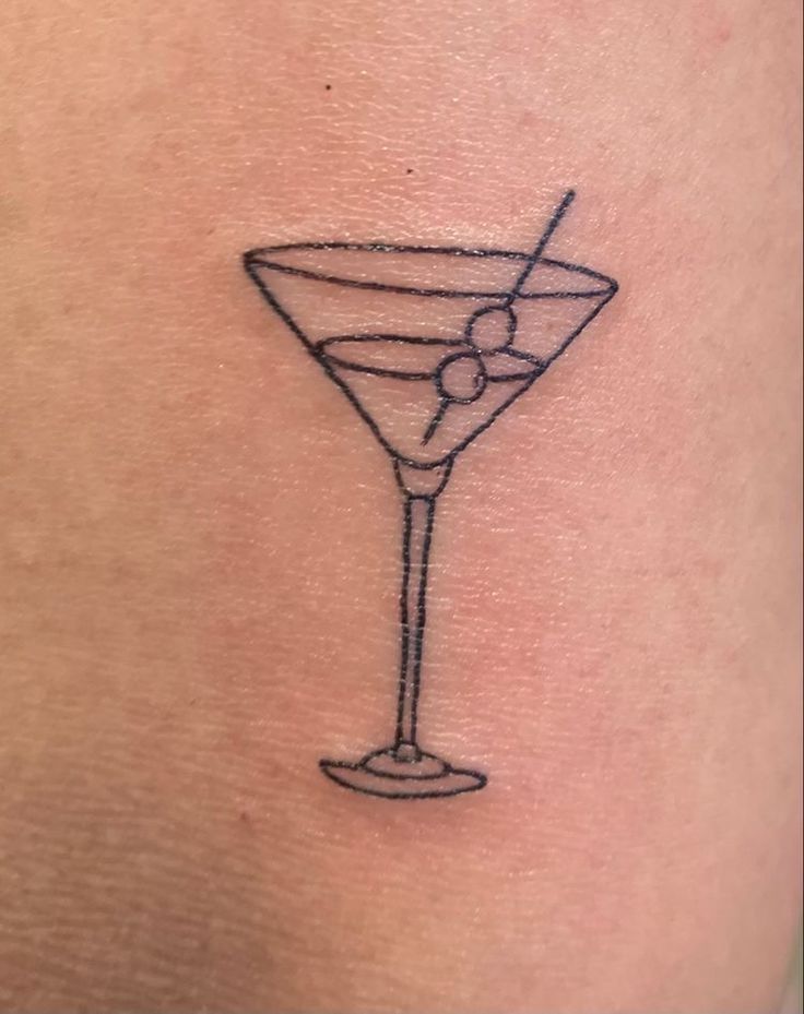 a small martini tattoo on the back of a woman's shoulder