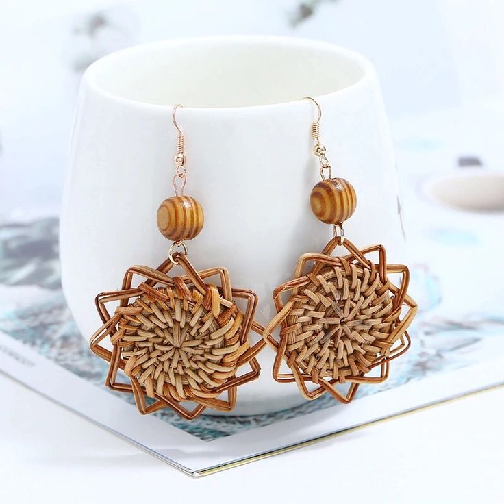 a pair of earrings sitting on top of a white cup