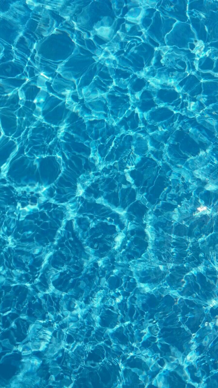 the blue water is reflecting sunlight and ripples on it's surface, as seen from above