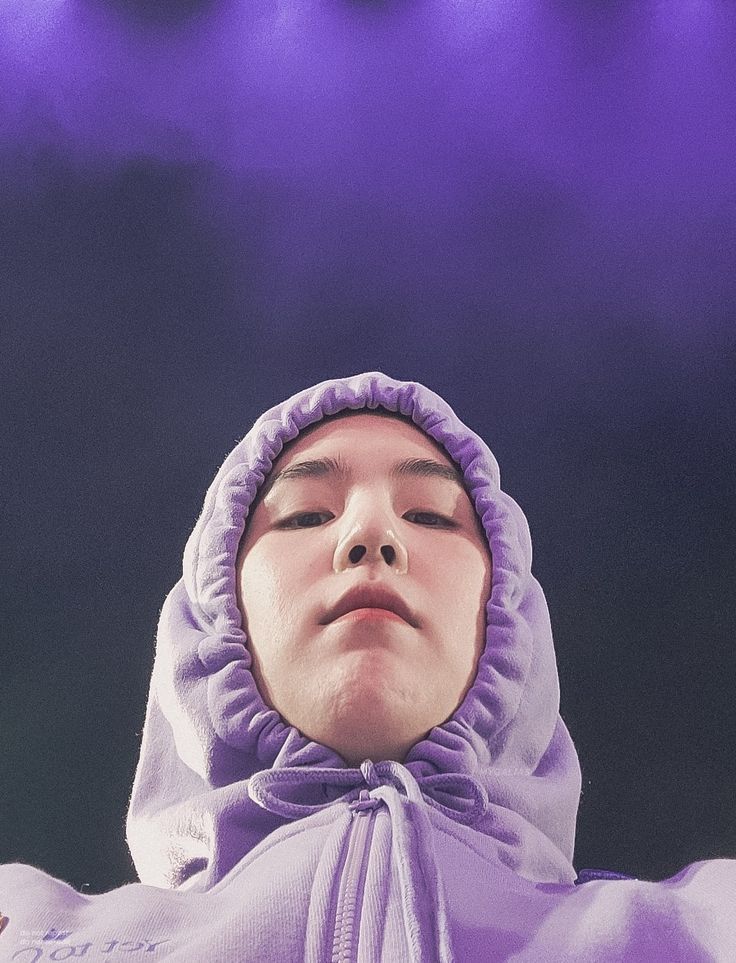 a woman with her eyes closed wearing a purple hoodie and looking up at the sky