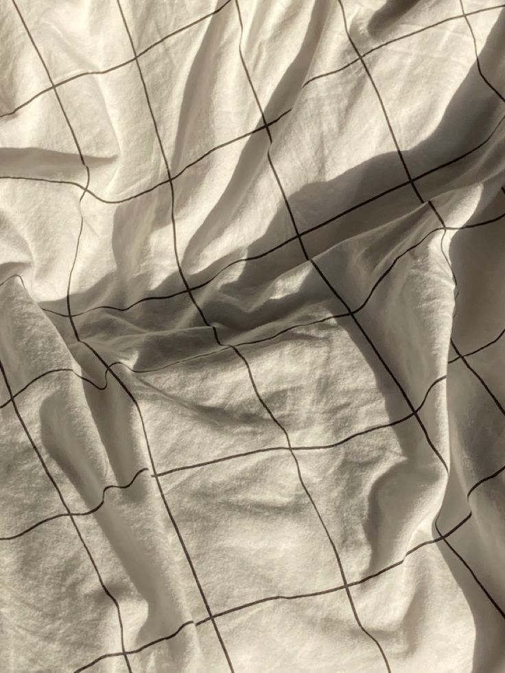 an unmade bed with white sheets and black lines on it