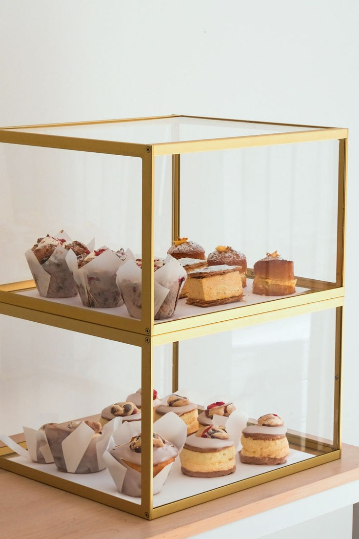 three tiered display case filled with different types of cakes and pastries on top of each other