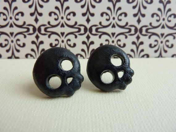 two black skulls with holes in them on a white tableclothed wallpaper background