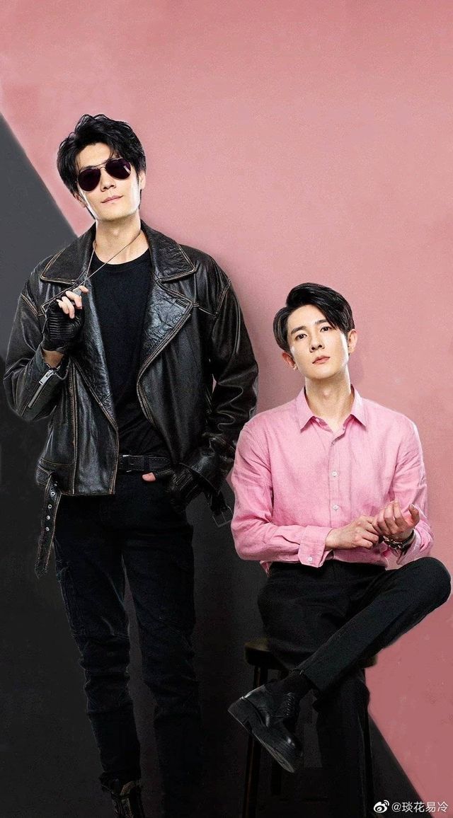 two young men standing next to each other in front of a pink and black wall