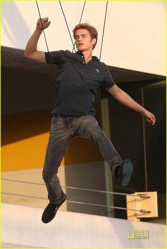 a man is suspended from the side of a building by ropes with his hands in the air