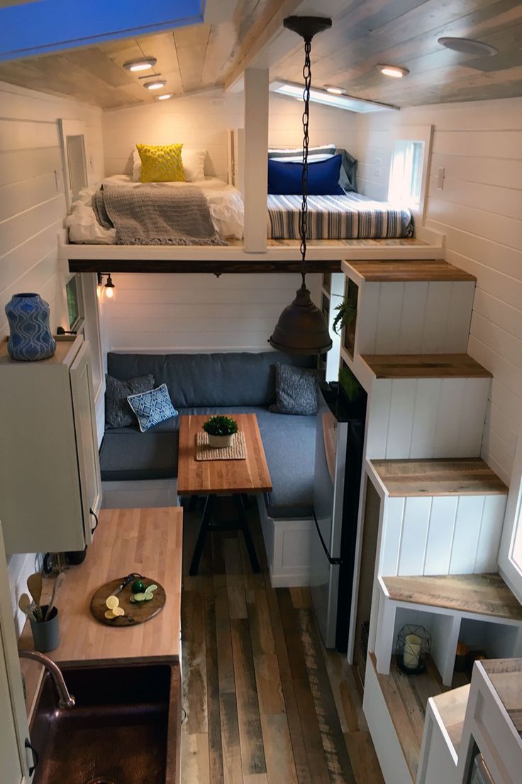 the interior of a tiny house with stairs leading up to the loft bed and kitchen