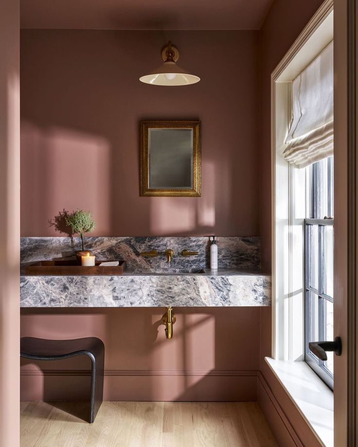 a bathroom with pink walls and marble counter tops