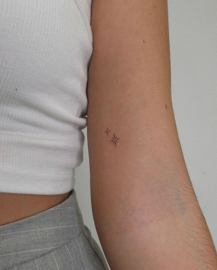 a woman's arm with a tiny star tattoo on the left side of her right arm