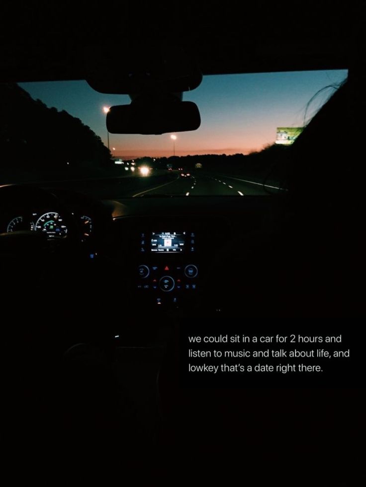 the view from inside a car at night with lights in the distance and on the dashboard