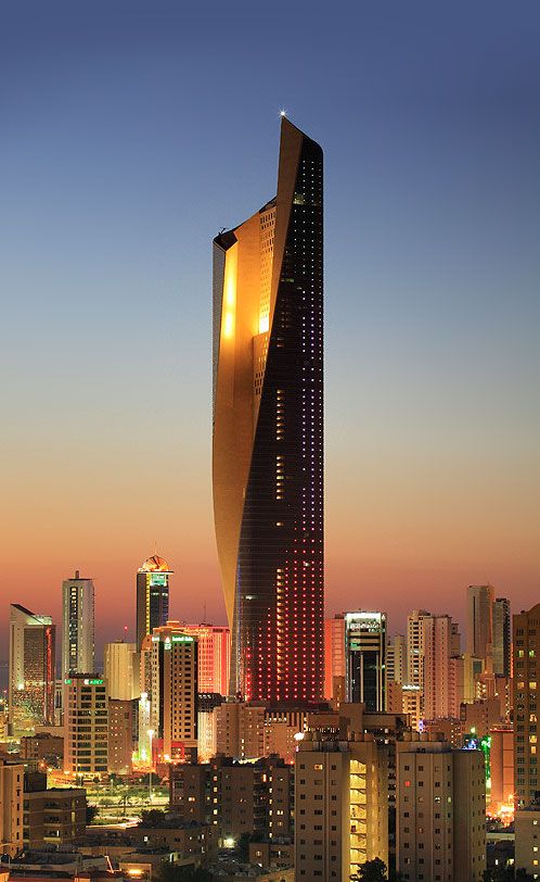 the tall building is lit up at night in front of other city buildings and skyscrapers