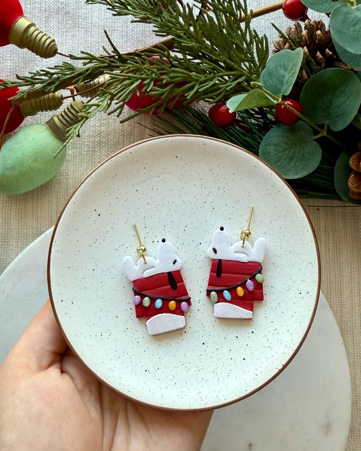 someone is holding up some christmas decorations on their earwires in front of a plate