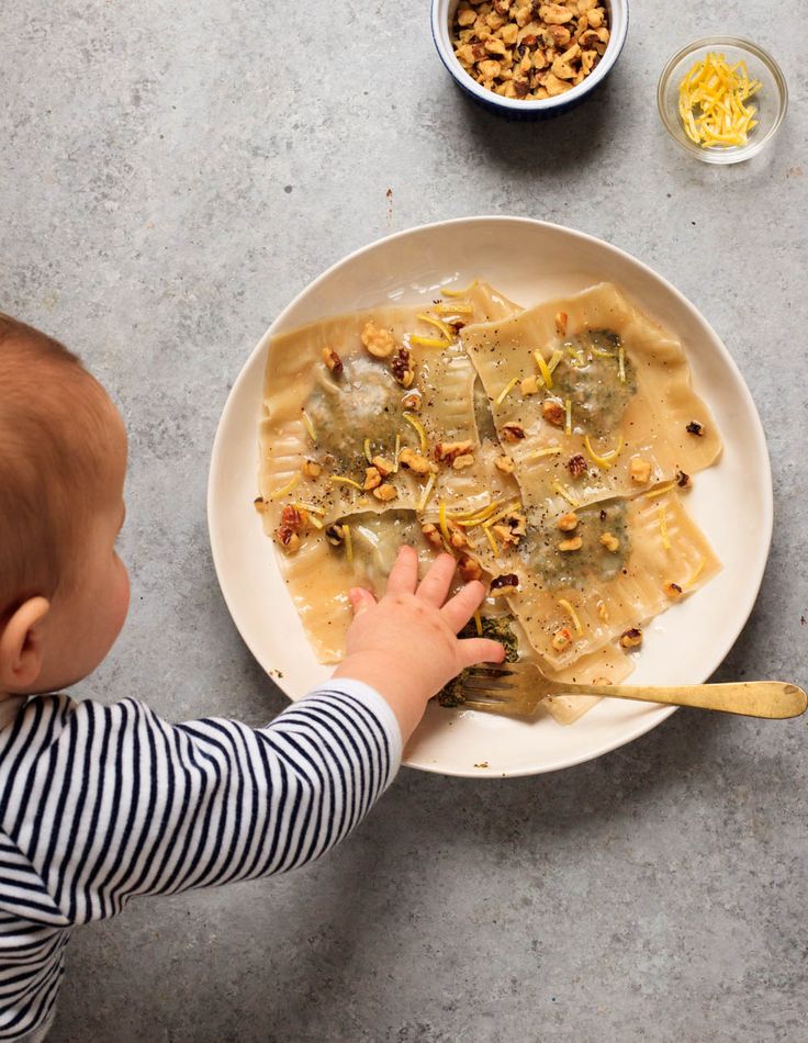 a toddler reaching for food on a plate