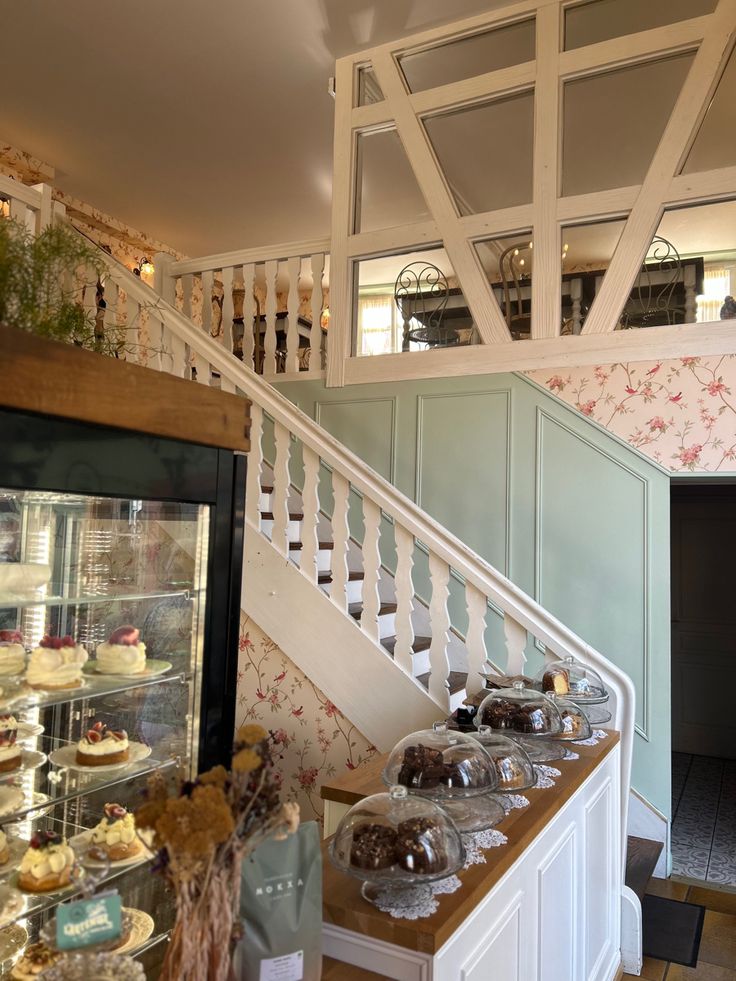 a display case filled with lots of cupcakes and pastries next to a stair case