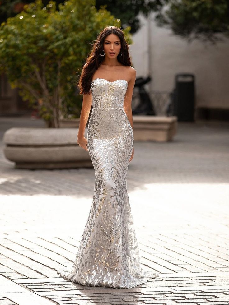 a model walks down the runway in a silver gown