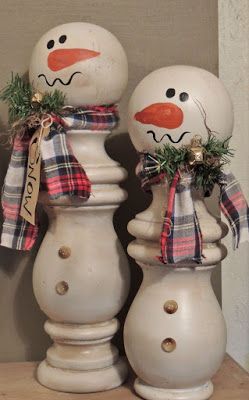 two snowmen standing next to each other on top of a wooden table in front of a wall