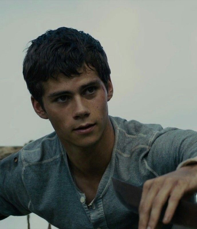 a young man is leaning on a fence