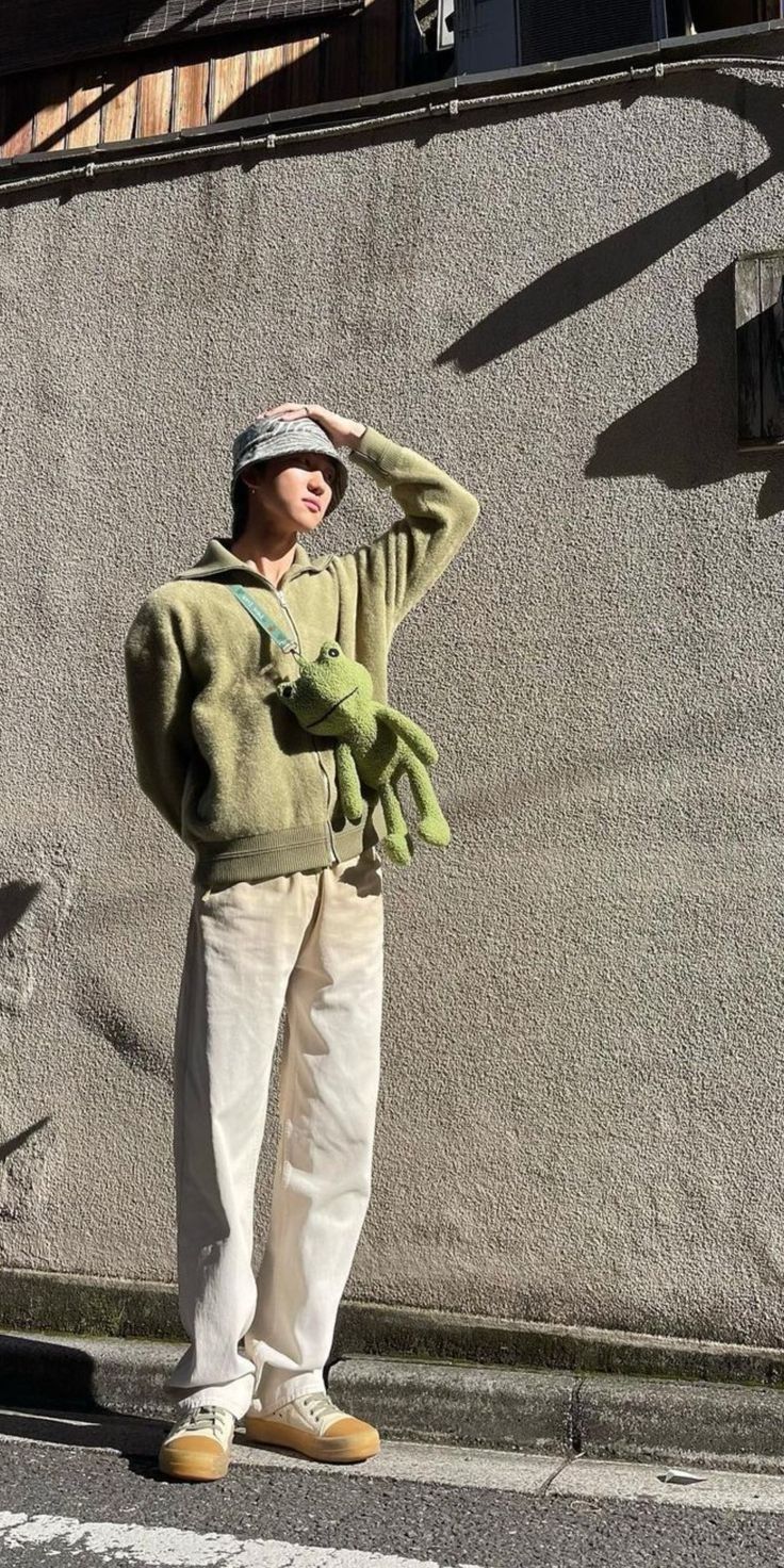 a man standing in front of a building with his hands on his head and wearing a hat