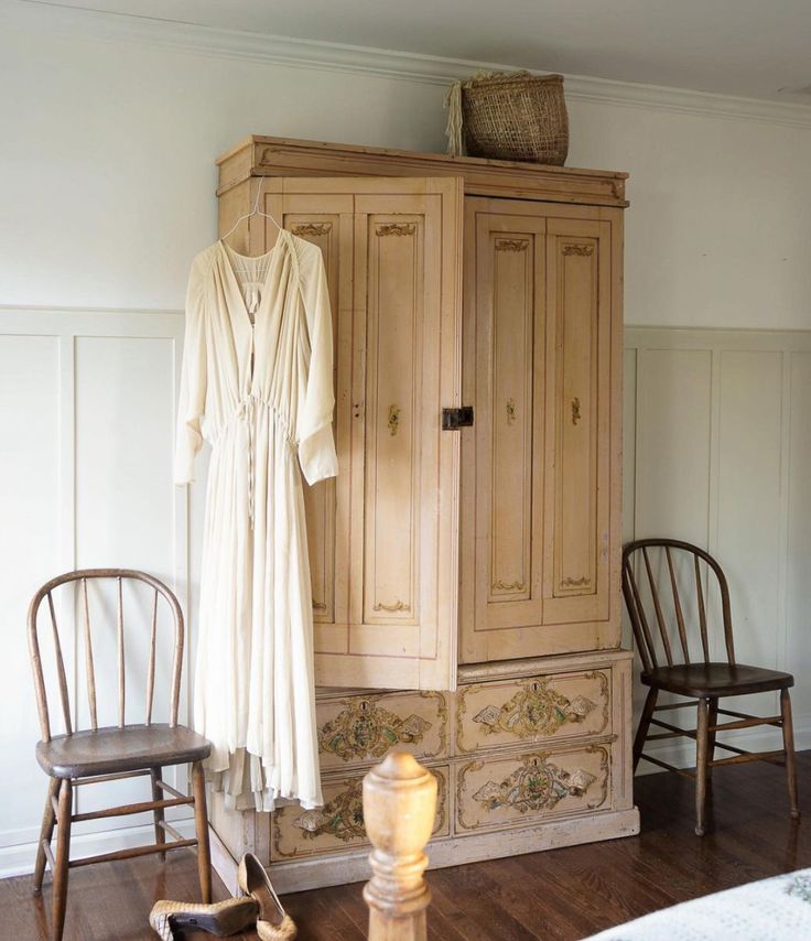 an antique armoire and two chairs in a room