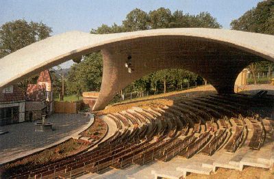 an outdoor seating area with rows of seats on either side and trees in the background