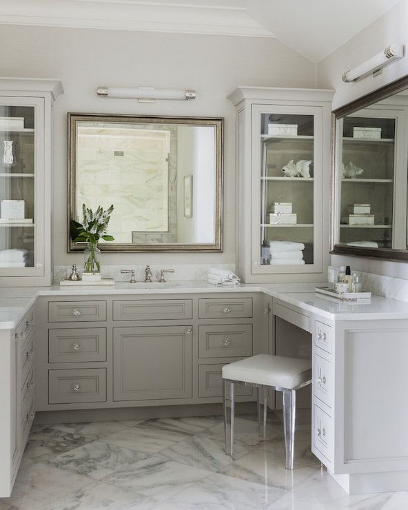 a bathroom with marble flooring and white cabinetry, along with large mirrors on the wall