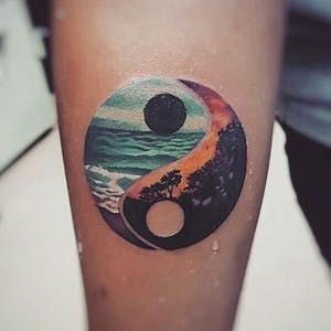 a person with a small tattoo on their arm that has an image of a beach and tree in it