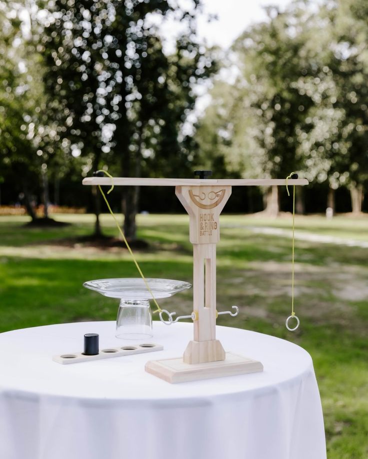 a table with a scale on top of it in the middle of some grass and trees