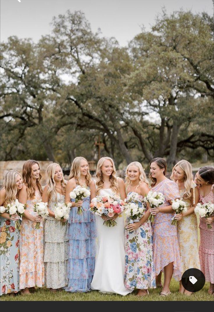 a group of women standing next to each other holding bouquets in their hands and laughing