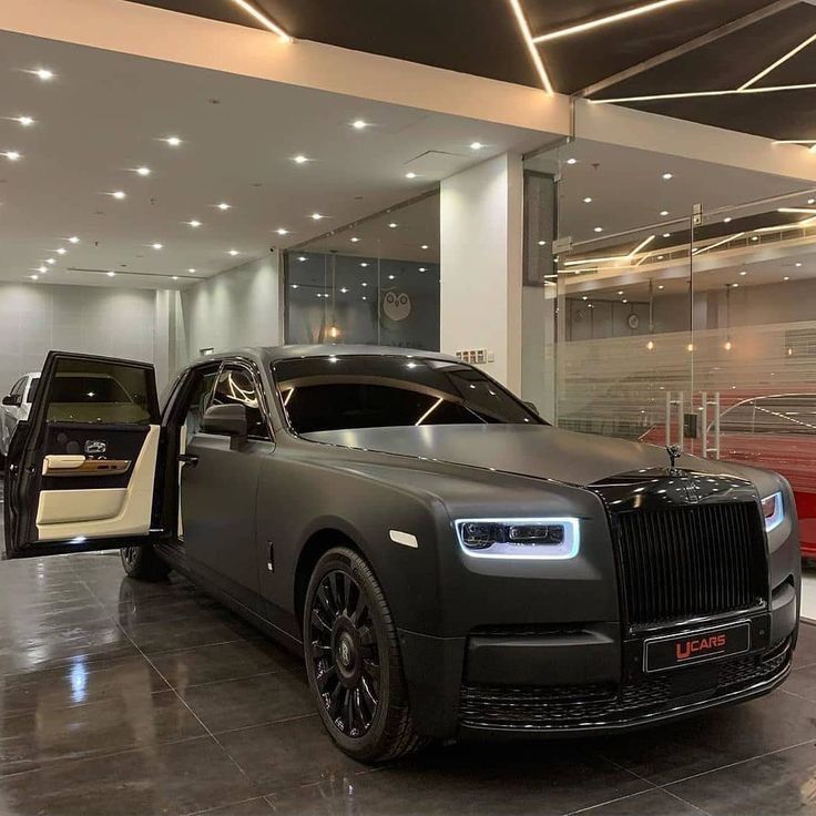 two rolls royces are parked in a showroom with their doors open to reveal the interior