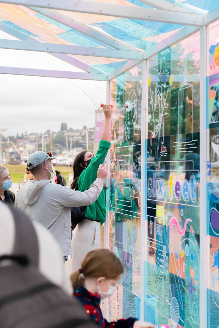 people are looking at artwork on the side of a building with many colors and shapes