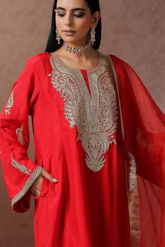 Red pheran with gold Kashmiri tilla embroidery in floral pattern on yoke. Paired with pant and fringe lace bordered dupatta.
Components: 3
Pattern: Embroidery
Type Of Work: Kashmiri Tilla
Neckline: Round
Sleeve Type: Full sleeves
Fabric: Silk, Crepe, Organza, Lining: Cotton
Color: Red
Other Details: 
Contrast pant
Side pockets on kurta
Fringe lace bordered dupatta
Approx. weight: 1 kgs
Length:
Kurta: 42 inches
Pant: 38 inches
Model height: 5ft 7inches, wearing size S
Occasion: Mehendi and Haldi Elegant Traditional Wear With Gota Work For Celebration, Elegant Red Raw Silk Salwar Kameez, Elegant Gold Embroidery Dupatta For Festivals, Elegant Gold Embroidered Dupatta For Festivals, Elegant Red Salwar Kameez With Resham Embroidery, Elegant Red Kurta With Zari Work, Red Intricate Embroidery Sets For Ceremonial, Elegant Red Traditional Wear, Elegant Gota Work Sets For Celebration