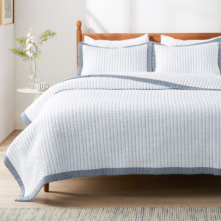 a bed with white and blue bedspread in a room