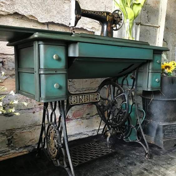 an old sewing machine is sitting on top of a table with flowers in the background