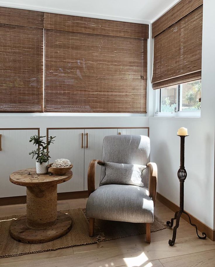 a chair and table in a room with wooden blinds on the window sills