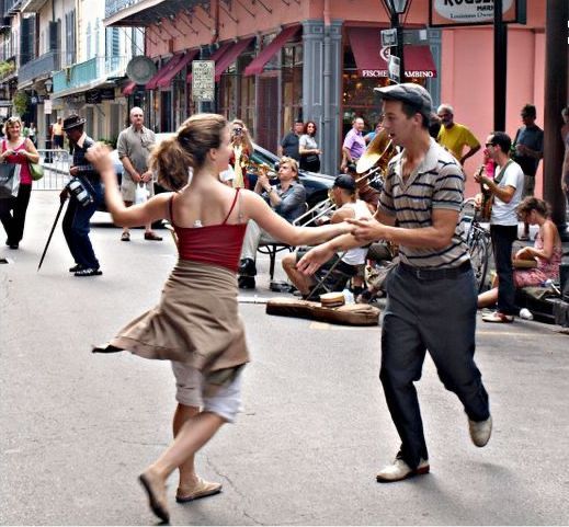 two people dancing in the middle of a city street with lots of people walking around