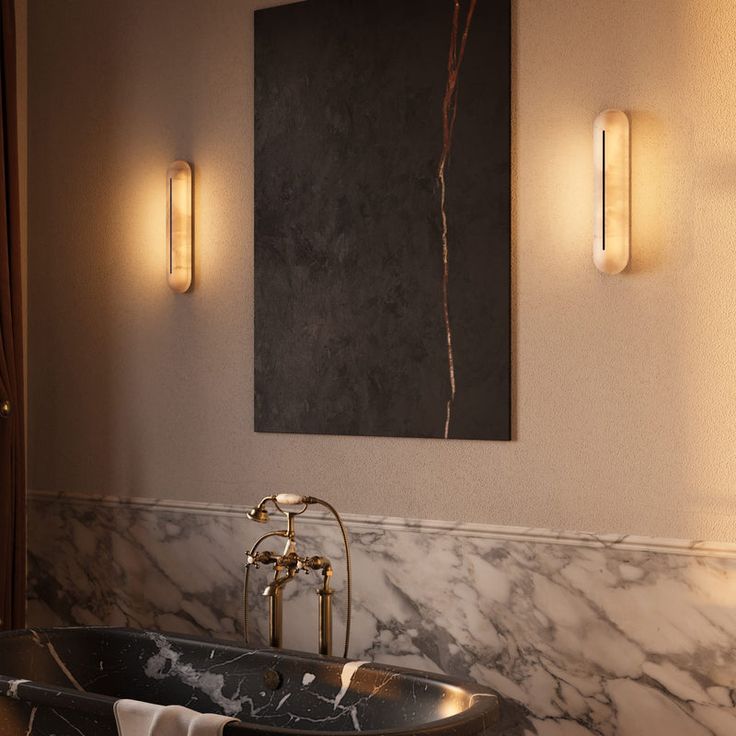 a bath tub sitting under two lights next to a painting on the wall in a bathroom