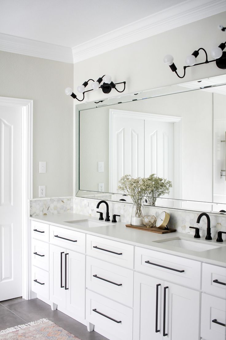 a white bathroom with double sinks and large mirrors on the wall above them is shown