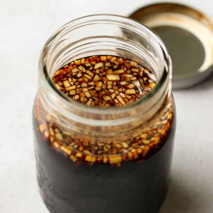 a jar filled with some kind of food on top of a white table next to a spoon