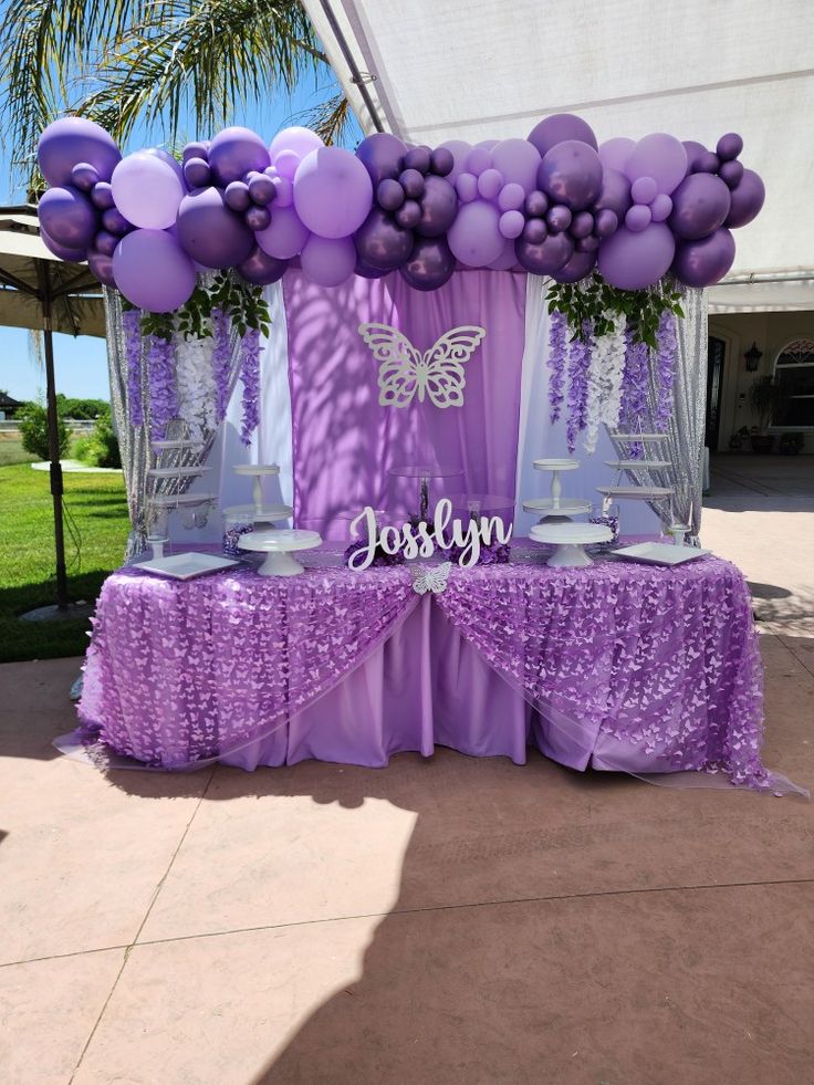 a table with purple and white balloons on it