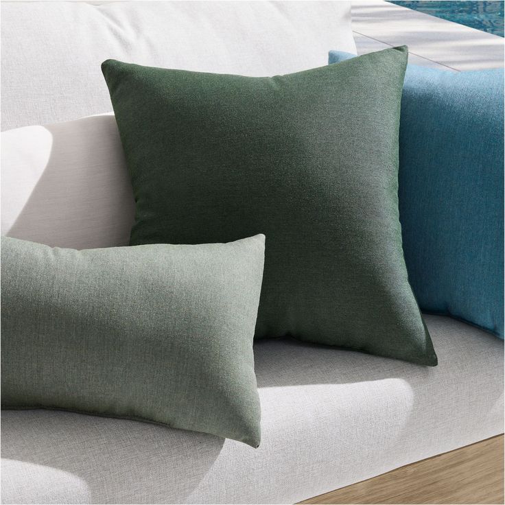 three pillows sitting on top of a white couch