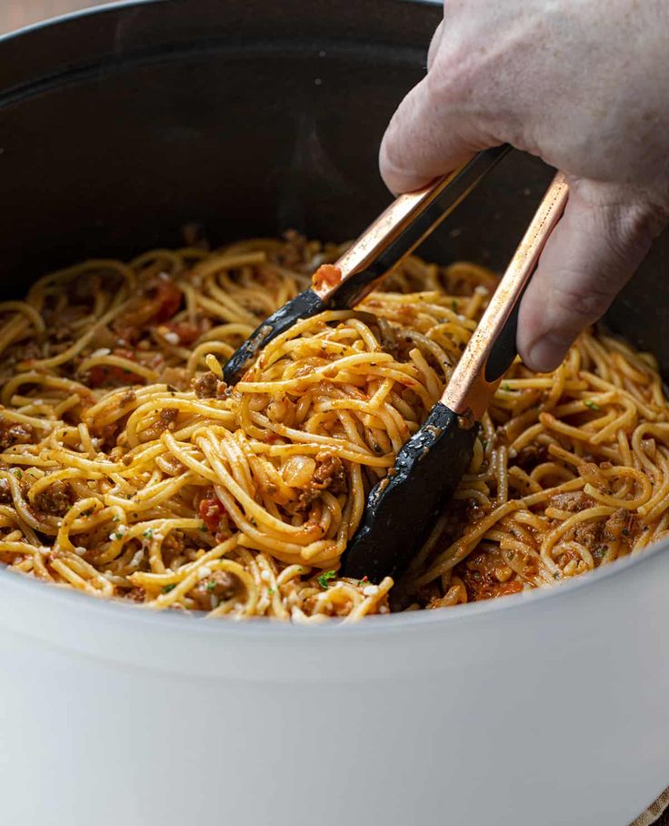 someone using chopsticks to stir spaghetti in a pot