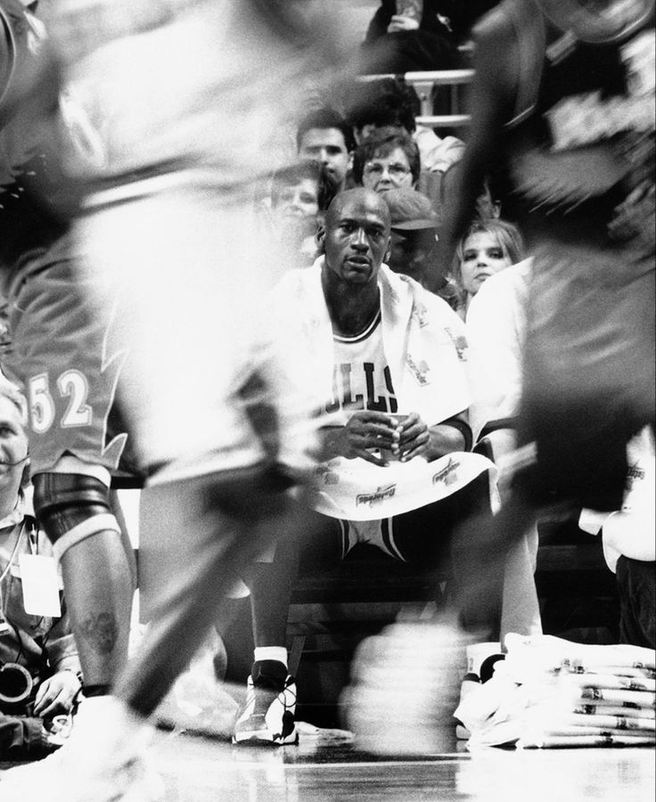 a black and white photo of a man holding a frisbee while sitting on the floor