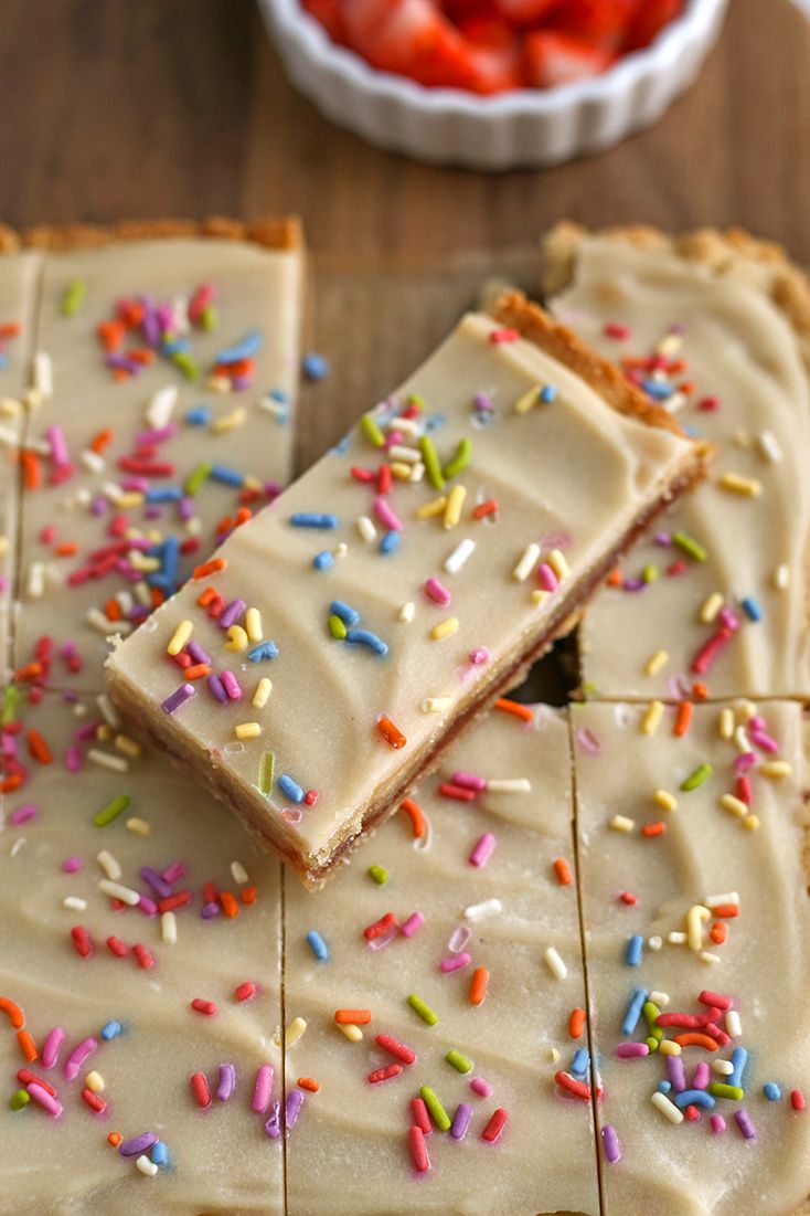 there are several pieces of cake with sprinkles on it and strawberries in the background