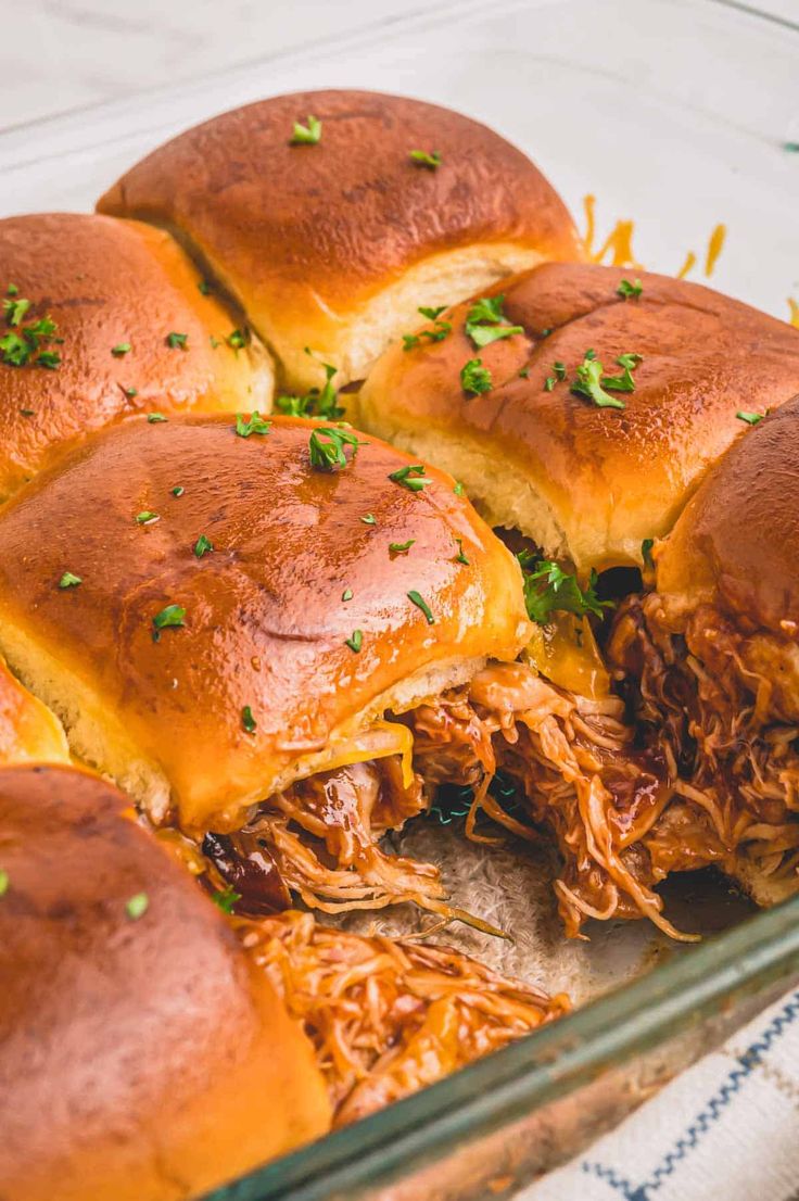 pulled pork sliders in a glass baking dish with cheese and parsley on top