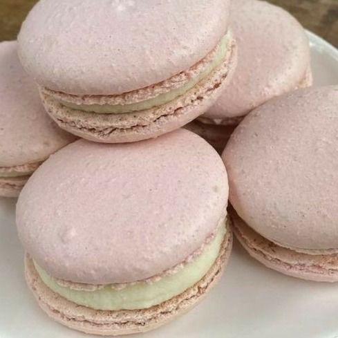 several pink macaroons on a white plate