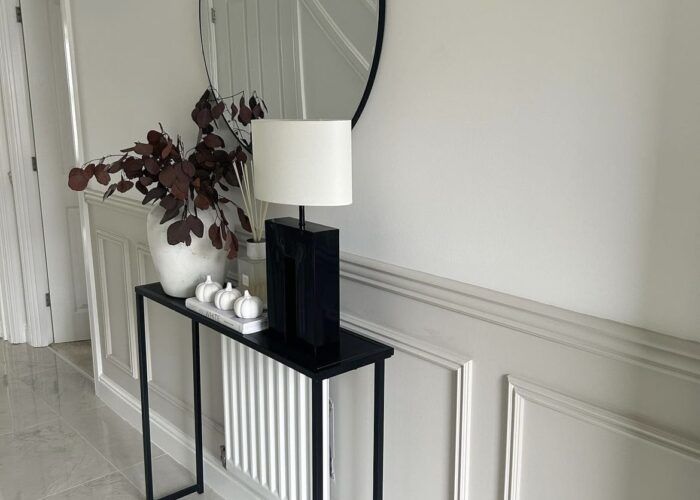 a black table with a white lamp and mirror on it next to a plant in a vase